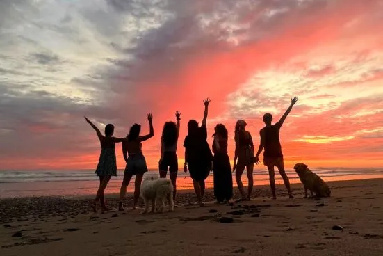 group of women celebrating sunset at the beach during a surf and yoga retreat