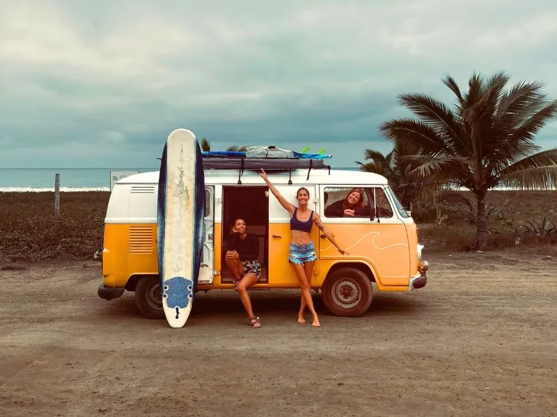 three women on a yellow van in a surf trip in Ecuador